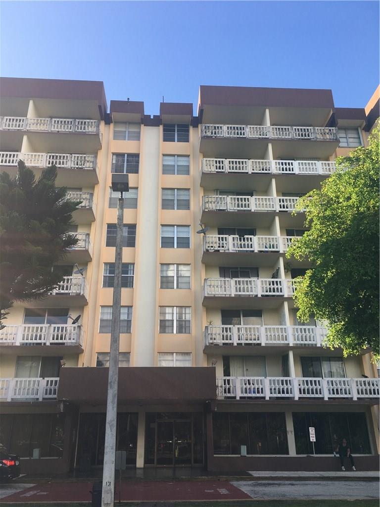 A multi-story apartment building features balconies with white railings and a central entrance — 15600 NW 7th Avenue # 421, Miami FL 33169, MIAMI, FL