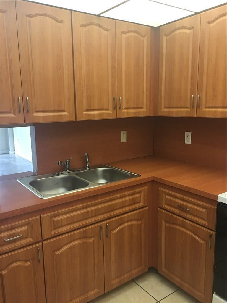 A kitchen features wood-grain cabinets, a stainless steel double sink, and laminate countertops — 15600 NW 7th Avenue # 421, Miami FL 33169, MIAMI, FL