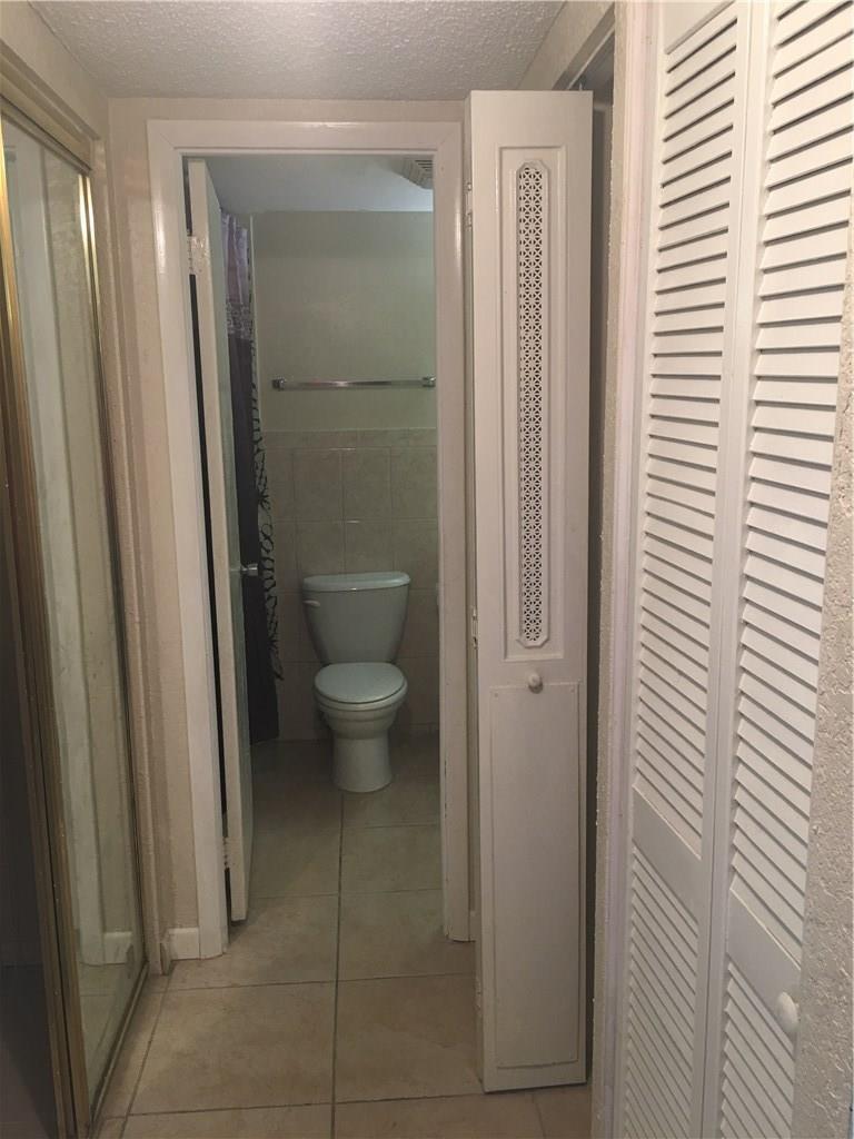 A bathroom features a toilet, tiled floors, and a partially open louvered door — 15600 NW 7th Avenue # 421, Miami FL 33169, MIAMI, FL