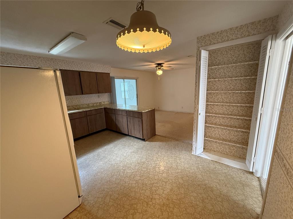 A kitchen with wood cabinets, laminate countertops, and a pantry with floral wallpaper — 27 KATHY DRIVE, ORMOND BEACH, FL