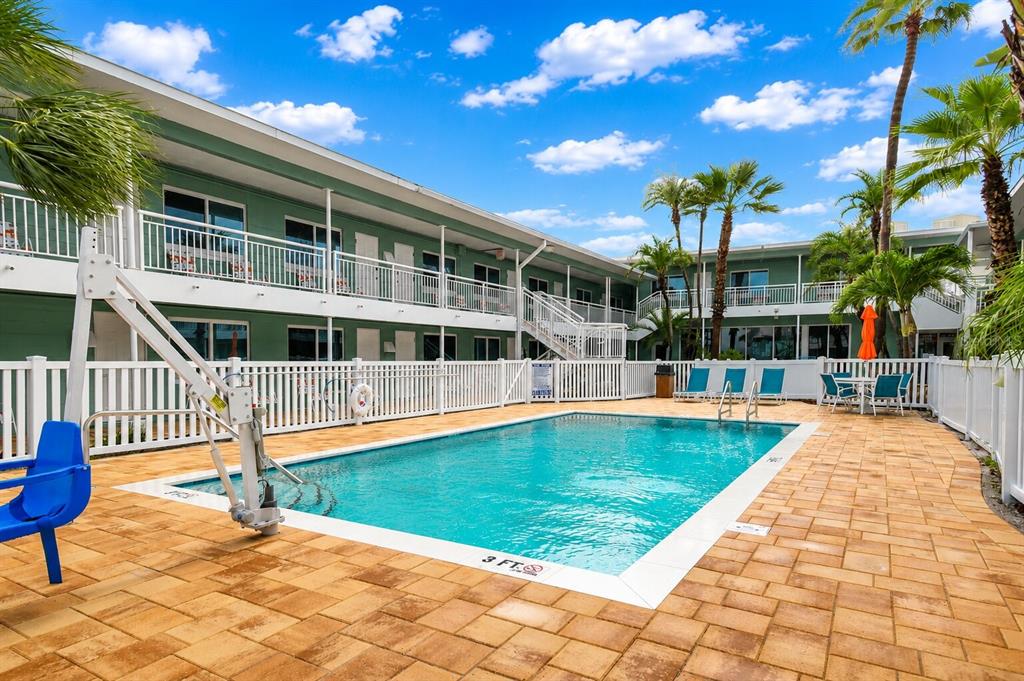 An outdoor swimming pool with a lift sits in a courtyard surrounded by a two-story building — 11730 GULF BOULEVARD UNIT 31, TREASURE ISLAND, FL