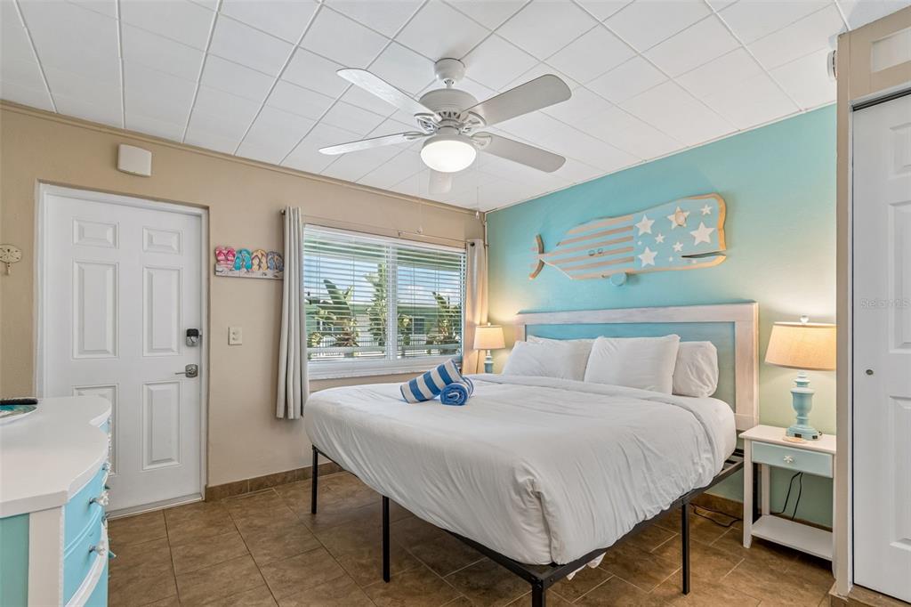 A bedroom features a queen bed, a whale wall decoration, and a ceiling fan — 11730 GULF BOULEVARD UNIT 31, TREASURE ISLAND, FL
