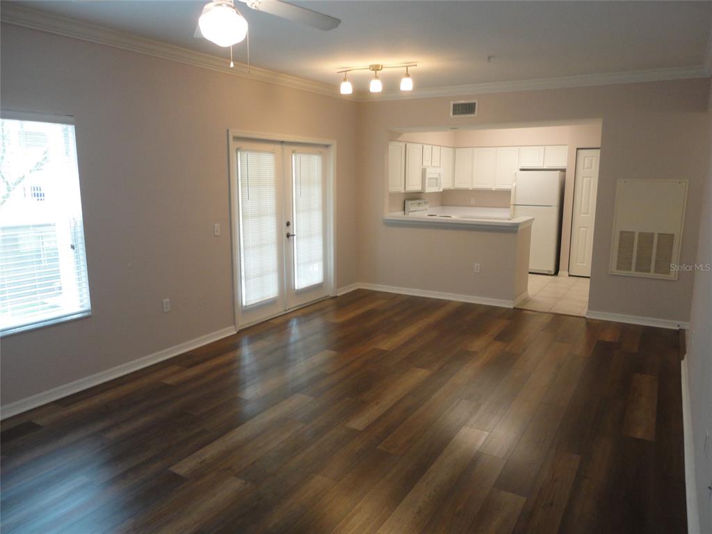 An open-concept living area with wood-look flooring, a ceiling fan, and an adjacent kitchen — 4820 SW 91ST TERRACE UNIT Q-202, GAINESVILLE, FL