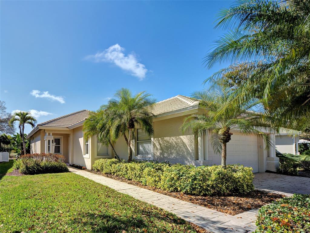A single-story house with a beige stucco exterior, a tiled roof, and palm trees — 311 LANSBROOK DRIVE, VENICE, FL