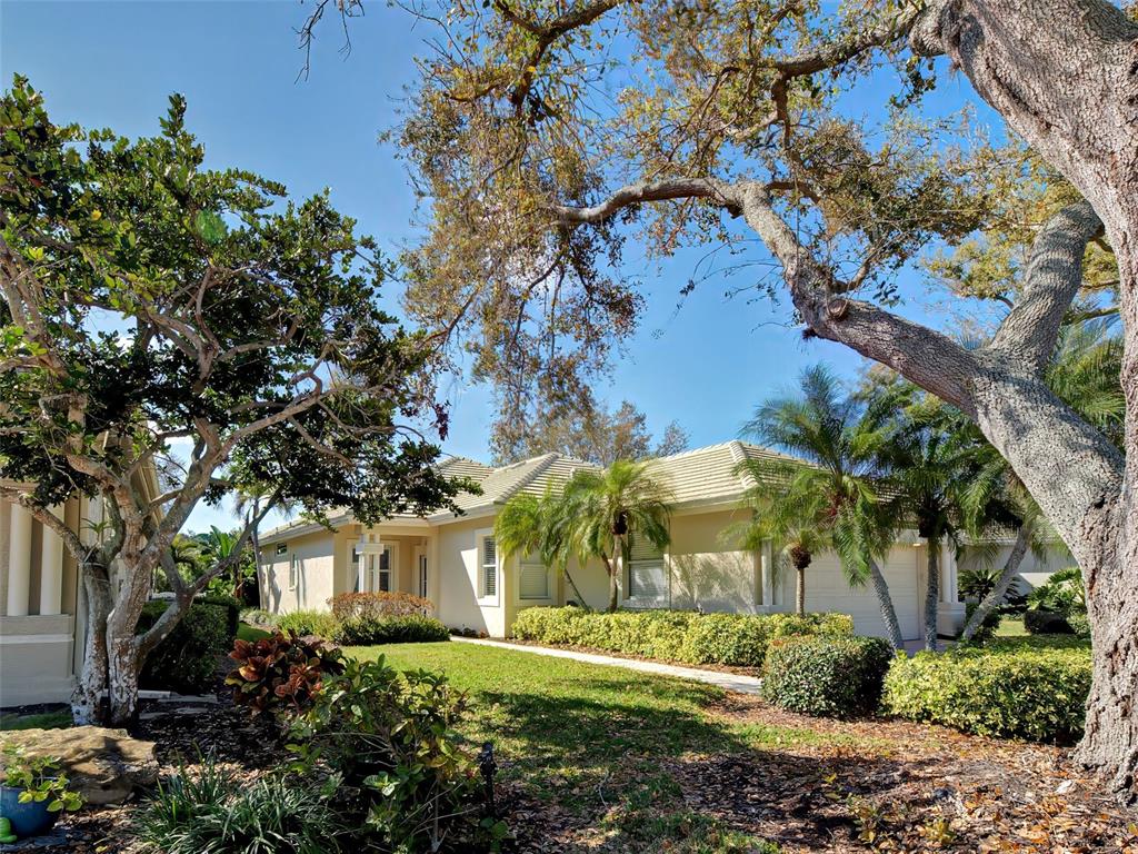 A single-story house with a light-colored exterior, a tiled roof, and surrounding trees and landscaping — 311 LANSBROOK DRIVE, VENICE, FL