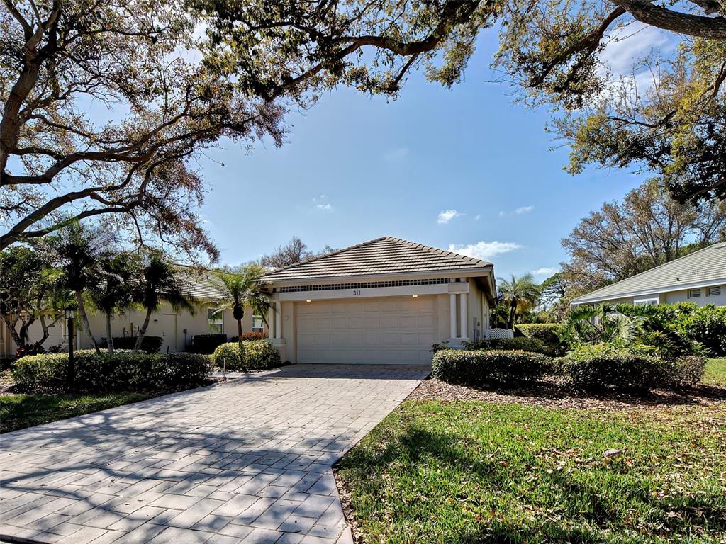 A single-story house with a beige garage, tile roof, and a paved driveway — 311 LANSBROOK DRIVE, VENICE, FL