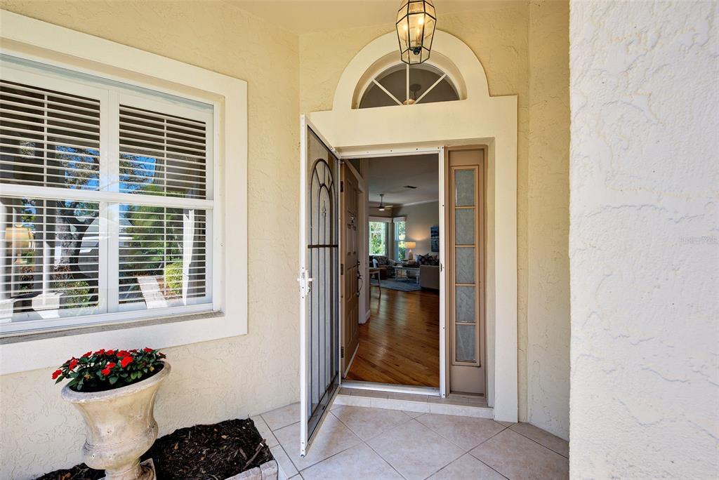 A front entryway with a screen door, a sidelight, and a view into the home — 311 LANSBROOK DRIVE, VENICE, FL