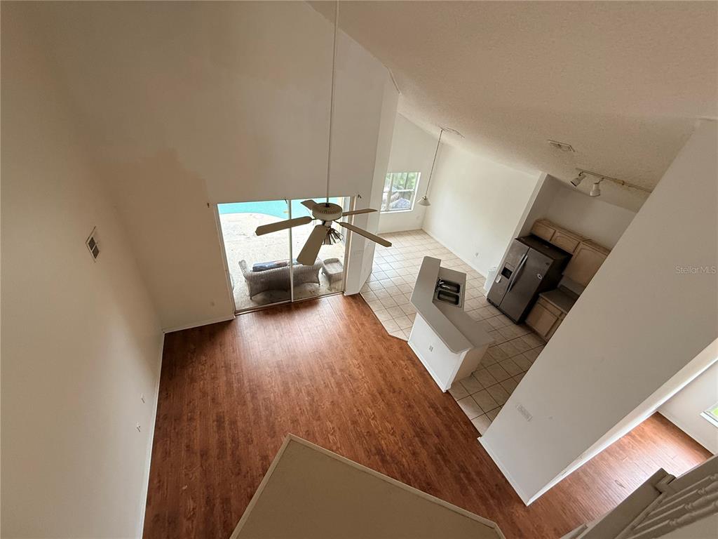 An elevated view shows a living room with wood floors, a kitchen, and a sliding door — 2918 BLOOMING ALAMANDA LOOP, KISSIMMEE, FL