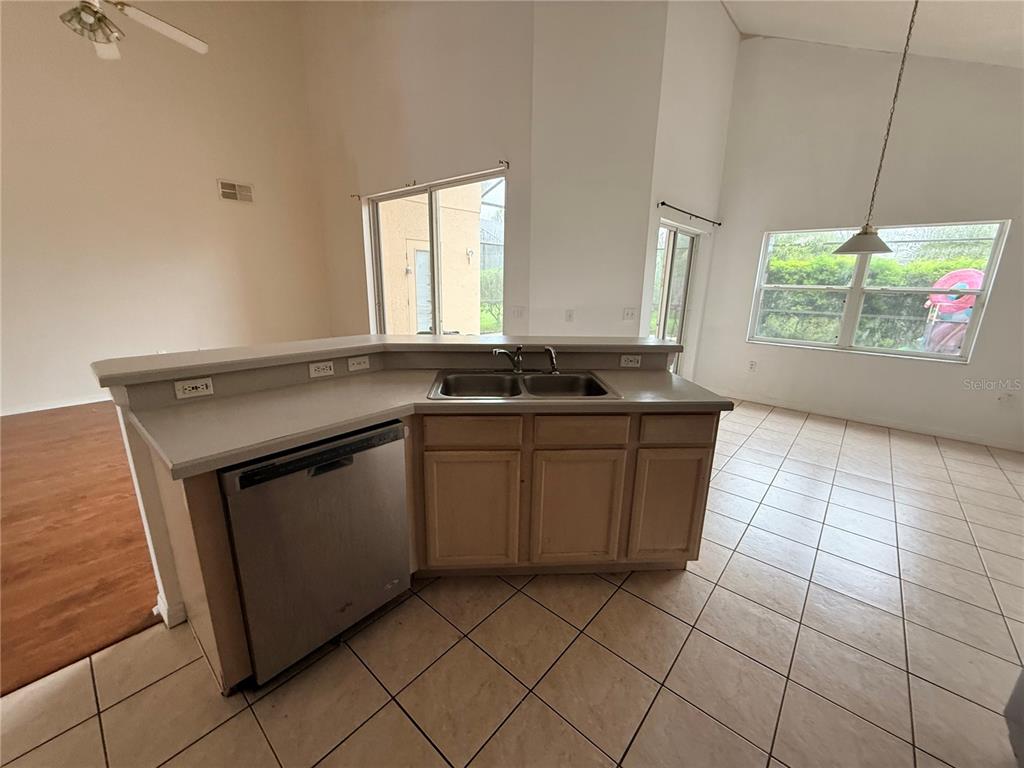 A kitchen features a stainless steel dishwasher, a double sink, and light-colored tile flooring — 2918 BLOOMING ALAMANDA LOOP, KISSIMMEE, FL