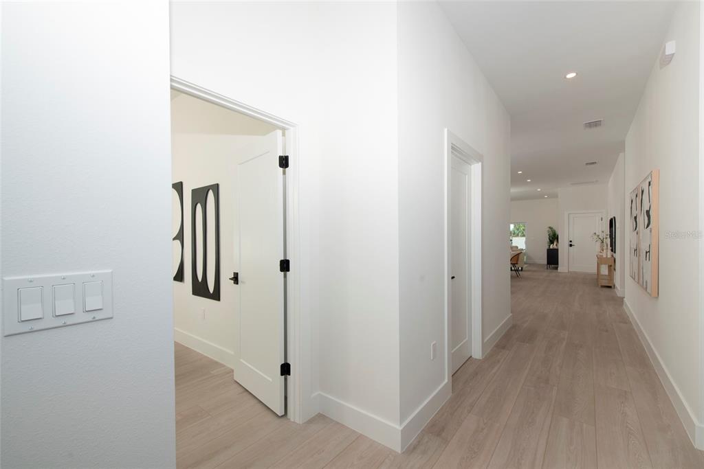 A hallway with light wood-look flooring leads toward an open living area with white walls — 5346 2ND AVENUE S, ST PETERSBURG, FL