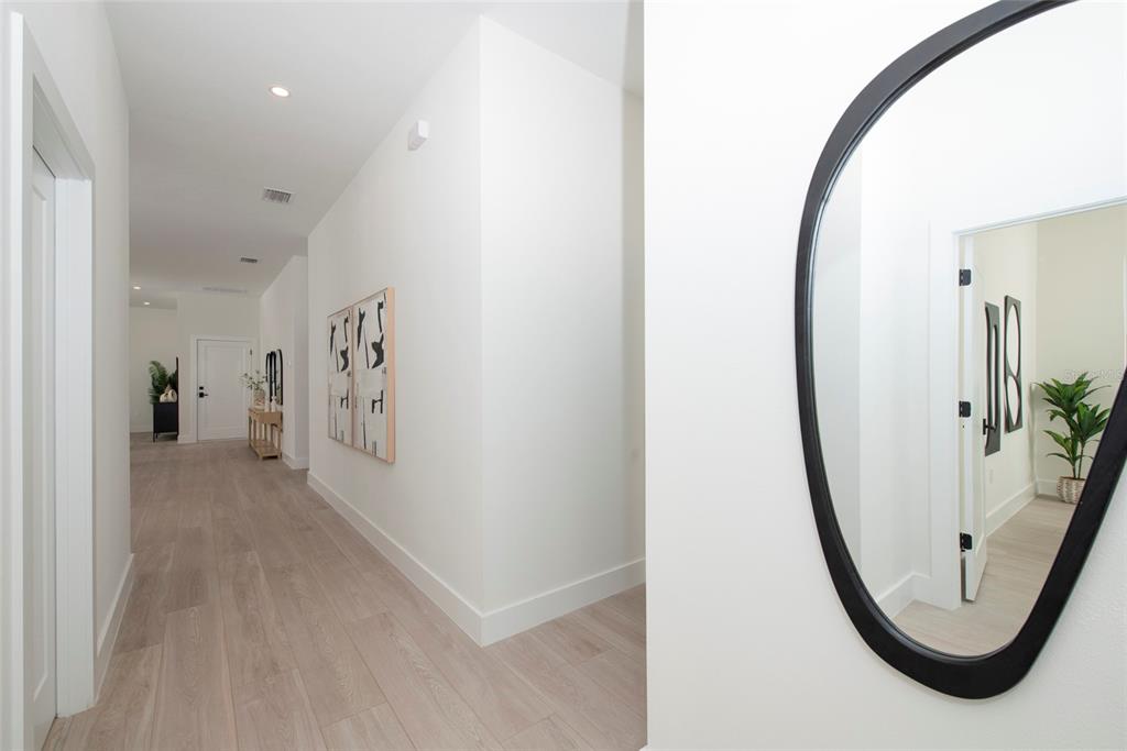 A bright hallway features light wood-look flooring, white walls, and a large black-framed mirror — 5346 2ND AVENUE S, ST PETERSBURG, FL