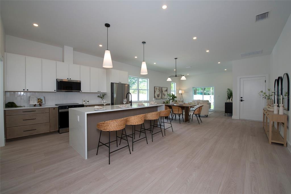 A modern kitchen features white cabinets, a large island with bar stools, and light flooring — 5346 2ND AVENUE S, ST PETERSBURG, FL