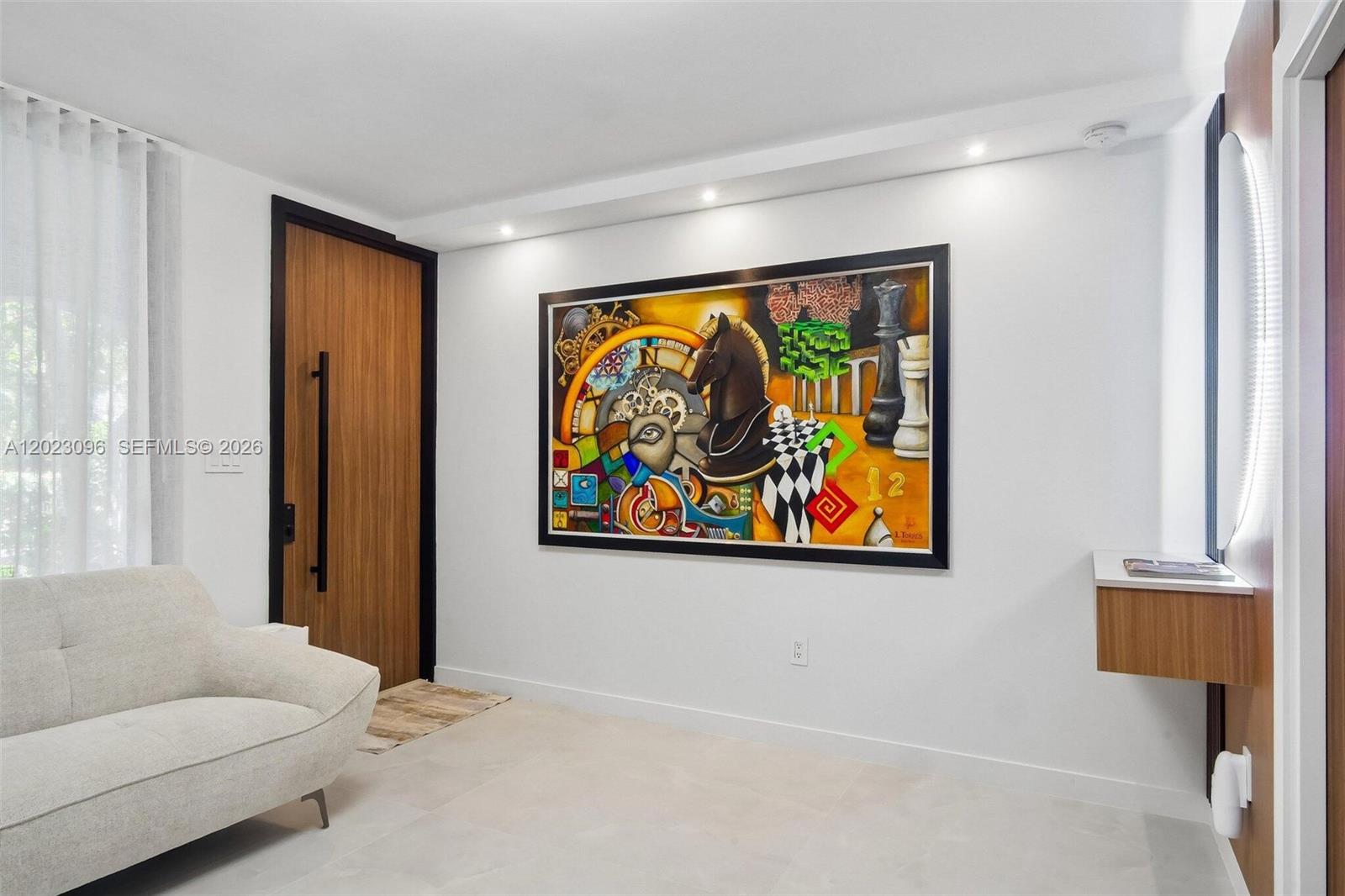 A modern room features a large abstract painting, a wood-paneled door, and a light-colored sofa — 425 Grapetree Dr # 211, Key Biscayne FL 33149, KEY BISCAYNE, FL