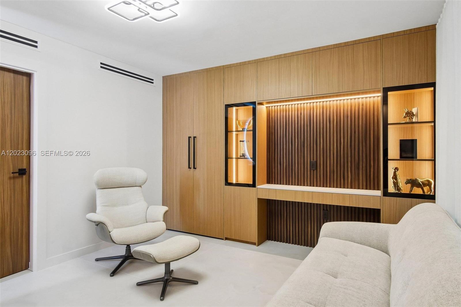 A modern room features a light wood wall unit with integrated shelving, a desk, and seating — 425 Grapetree Dr # 211, Key Biscayne FL 33149, KEY BISCAYNE, FL