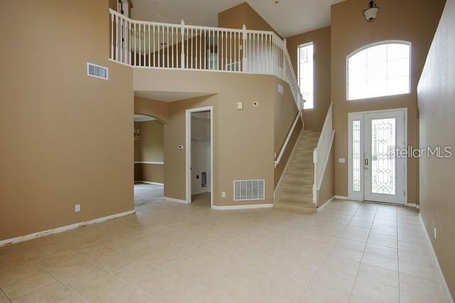 A spacious living area with tile floors, a staircase, and a second-floor balcony railing — 1643 STARGAZER TERRACE, SANFORD, FL
