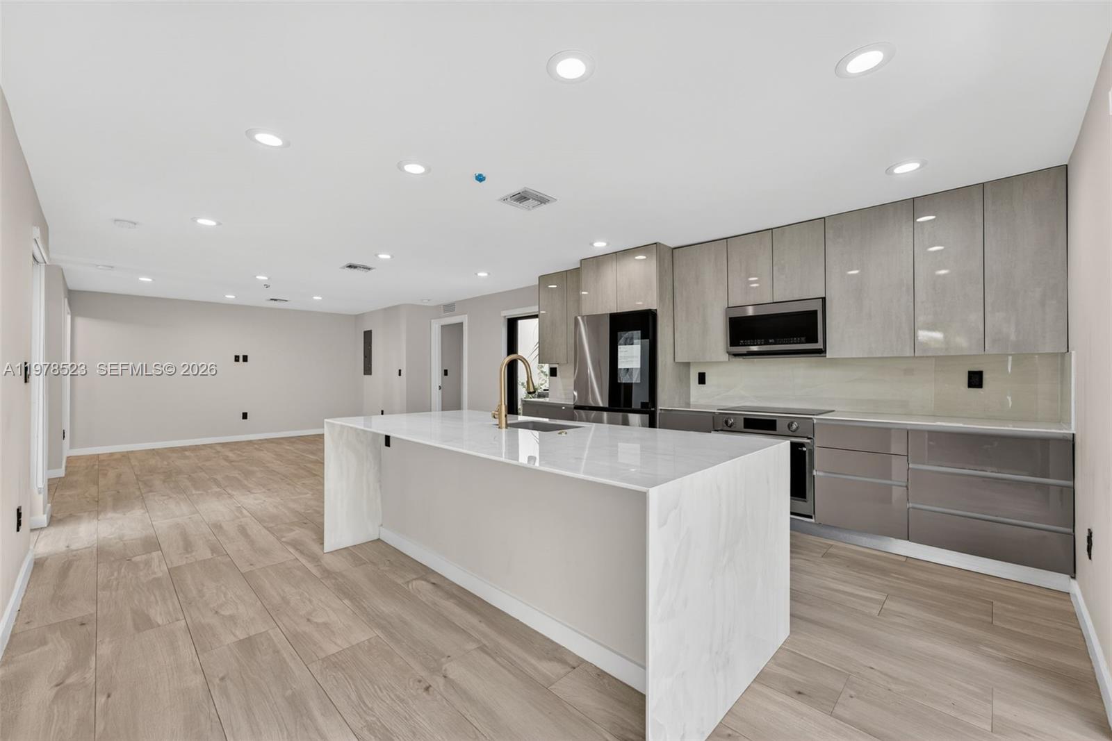 A modern kitchen features a white marble island, light wood-look flooring, and grey cabinetry — 5101 N Miami Ave, Miami FL 33137, MIAMI, FL