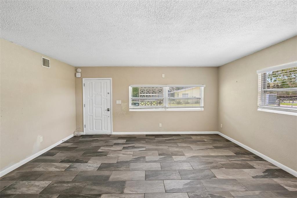 An empty room features light beige walls, white trim, and dark wood-look tile flooring — 114 LAKE JUDY LEE DRIVE, LARGO, FL