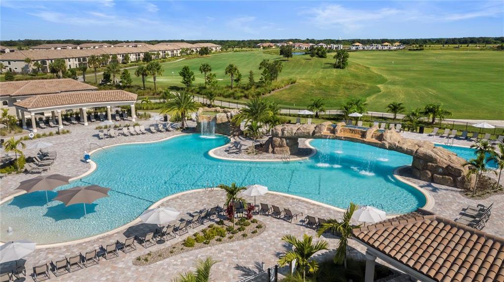 An aerial view of a resort-style swimming pool with rock waterfalls and surrounding lounge chairs — 18008 GAWTHROP DRIVE UNIT 402, LAKEWOOD RANCH, FL