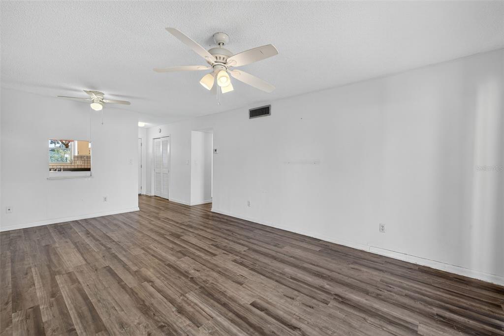 An empty room with white walls, wood-look flooring, and two ceiling fans — 2207 CROTON COURT UNIT 0, LEHIGH ACRES, FL