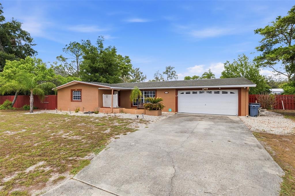 A single-story house with a tan stucco exterior, a two-car garage, and a concrete driveway — 10744 OSCEOLA DRIVE, NEW PORT RICHEY, FL