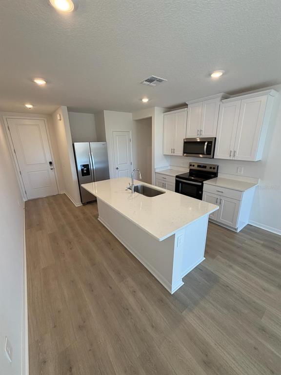 A modern kitchen features white cabinets, stainless steel appliances, and a central island with seating — 5229 NATIVE MILE LOOP, DAVENPORT, FL