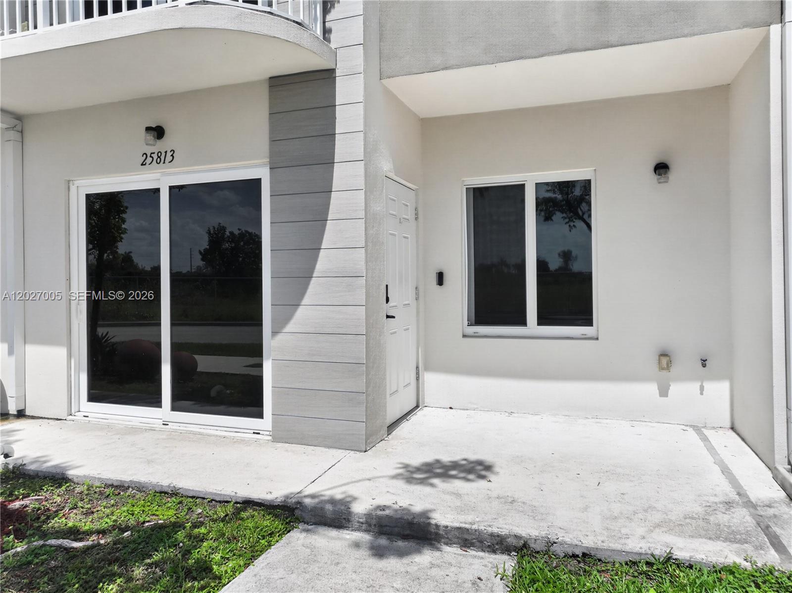 A ground-level patio features a sliding glass door, a white entry door, and a window — 25813 SW 145th Ave, Homestead FL 33032, HOMESTEAD, FL