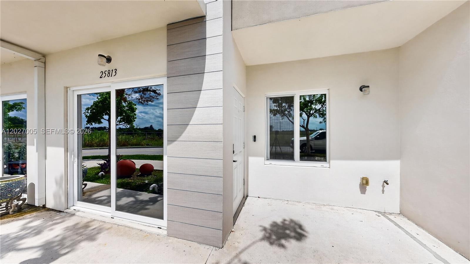 The exterior view shows a patio with a sliding glass door, a window, and a door — 25813 SW 145th Ave, Homestead FL 33032, HOMESTEAD, FL