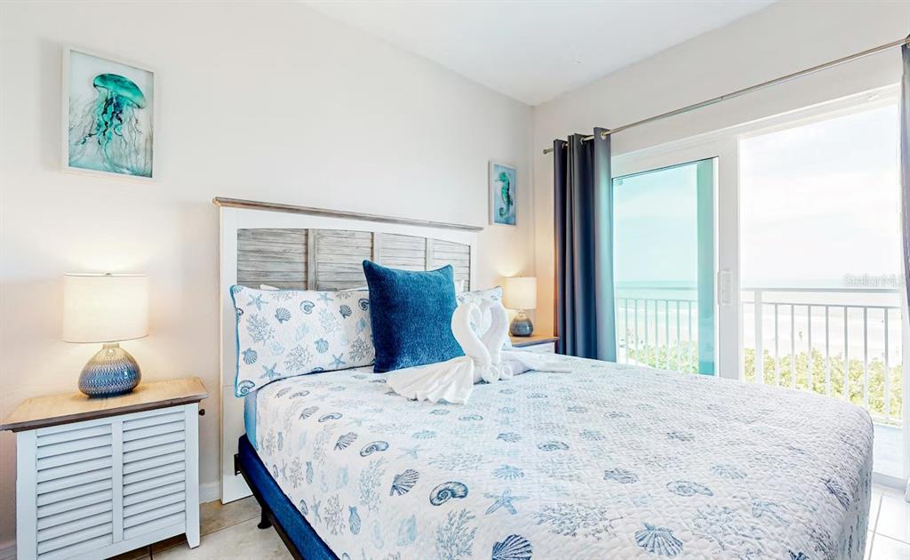 A bedroom features a bed with a seashell quilt, a balcony, and an ocean view — 611 S ATLANTIC AVENUE UNIT 4312, NEW SMYRNA BEACH, FL