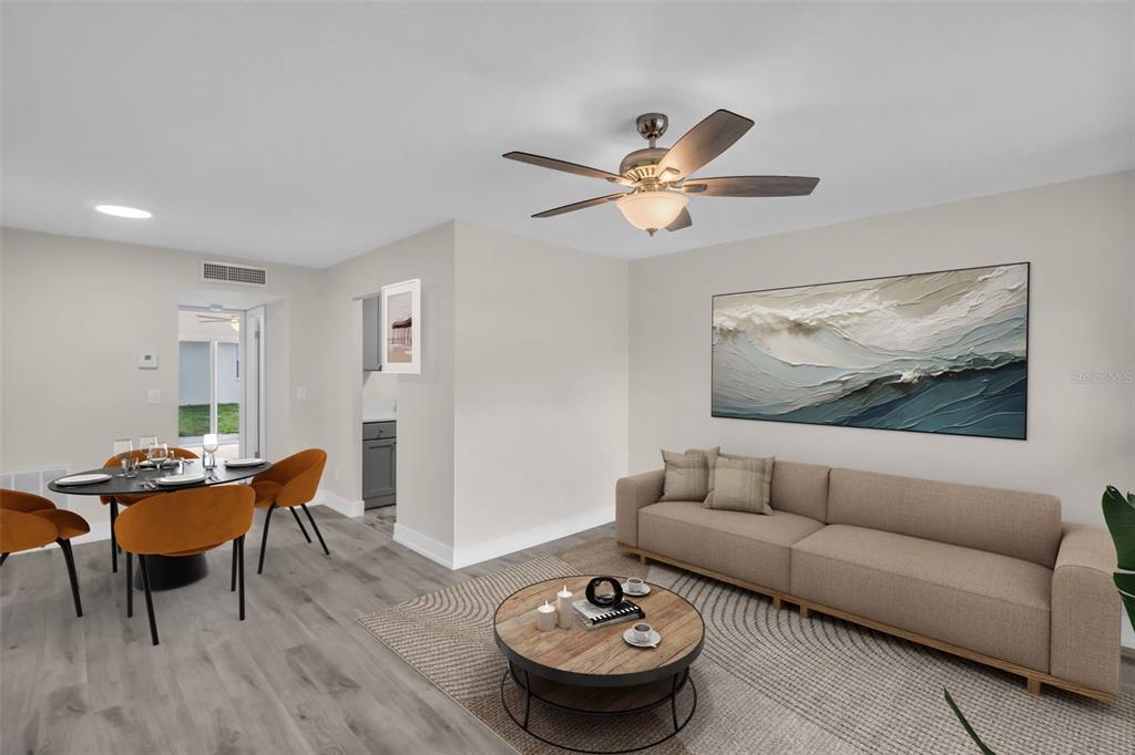 A living room and dining area feature light wood floors, a ceiling fan, and furniture — 24862 US HIGHWAY 19 N UNIT 1105, CLEARWATER, FL