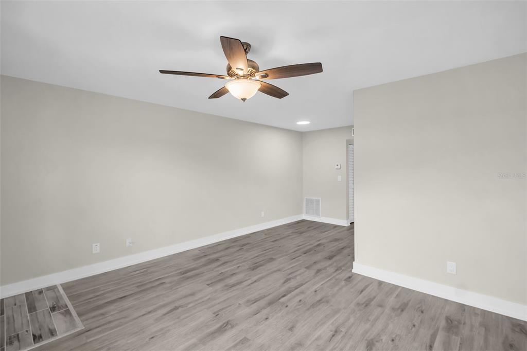 An empty room features light gray walls, wood-look flooring, and a ceiling fan — 24862 US HIGHWAY 19 N UNIT 1105, CLEARWATER, FL