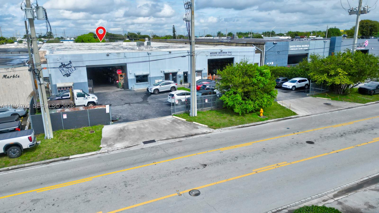 An exterior view of a commercial warehouse building with a parking lot and street frontage — 7957 NW 54th St, Doral FL 33166, DORAL, FL