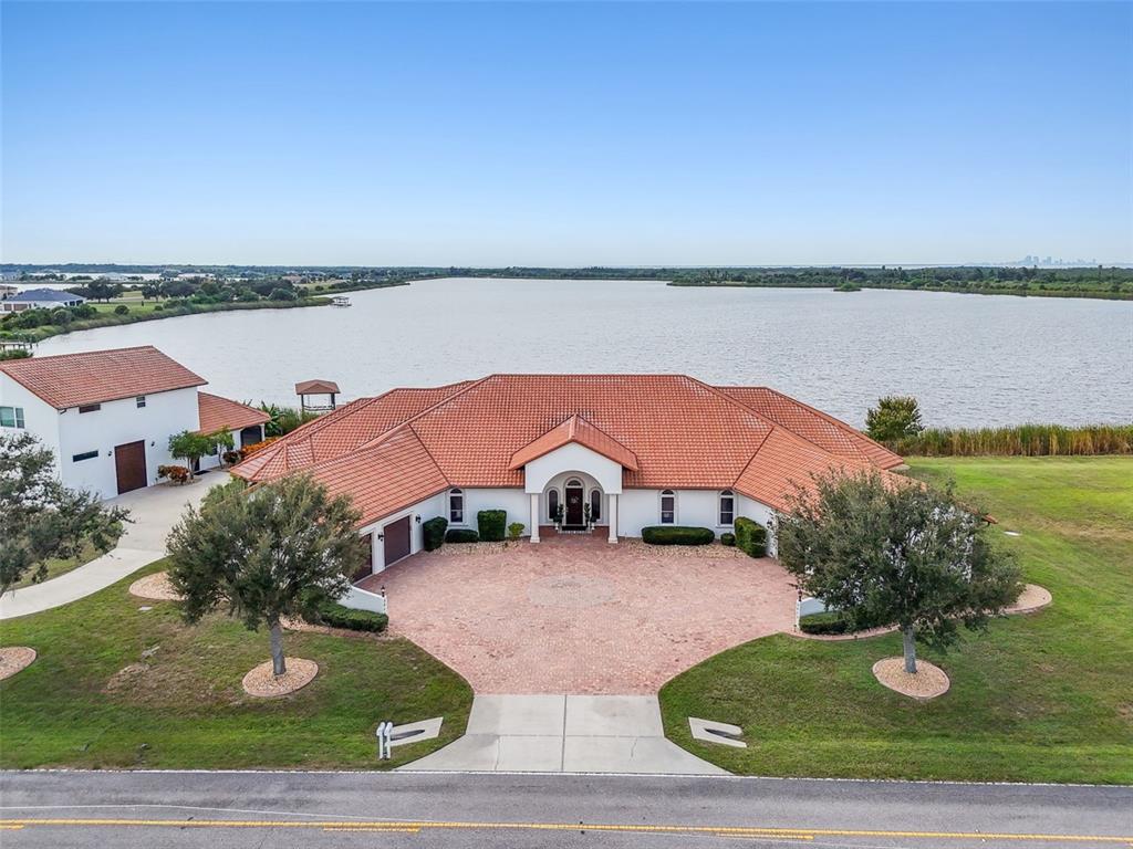 An aerial view shows a white house with a red tile roof and circular driveway — 3215 GULF CITY ROAD, RUSKIN, FL