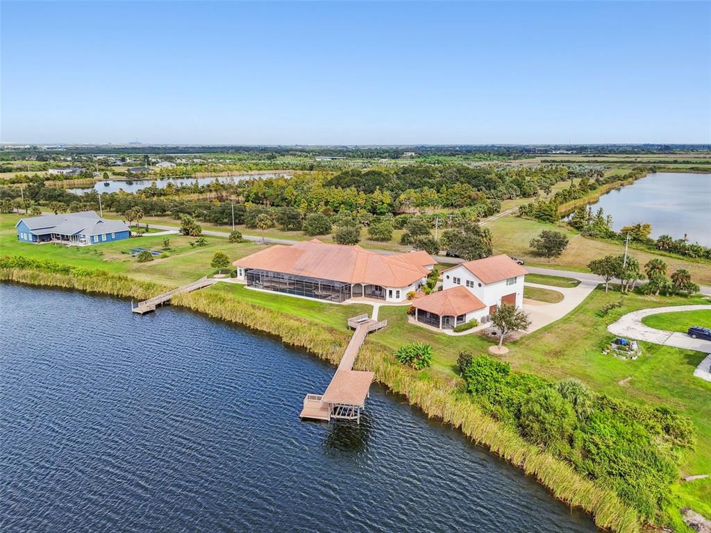 An aerial view shows a house with a screened pool and dock on a lake — 3215 GULF CITY ROAD, RUSKIN, FL