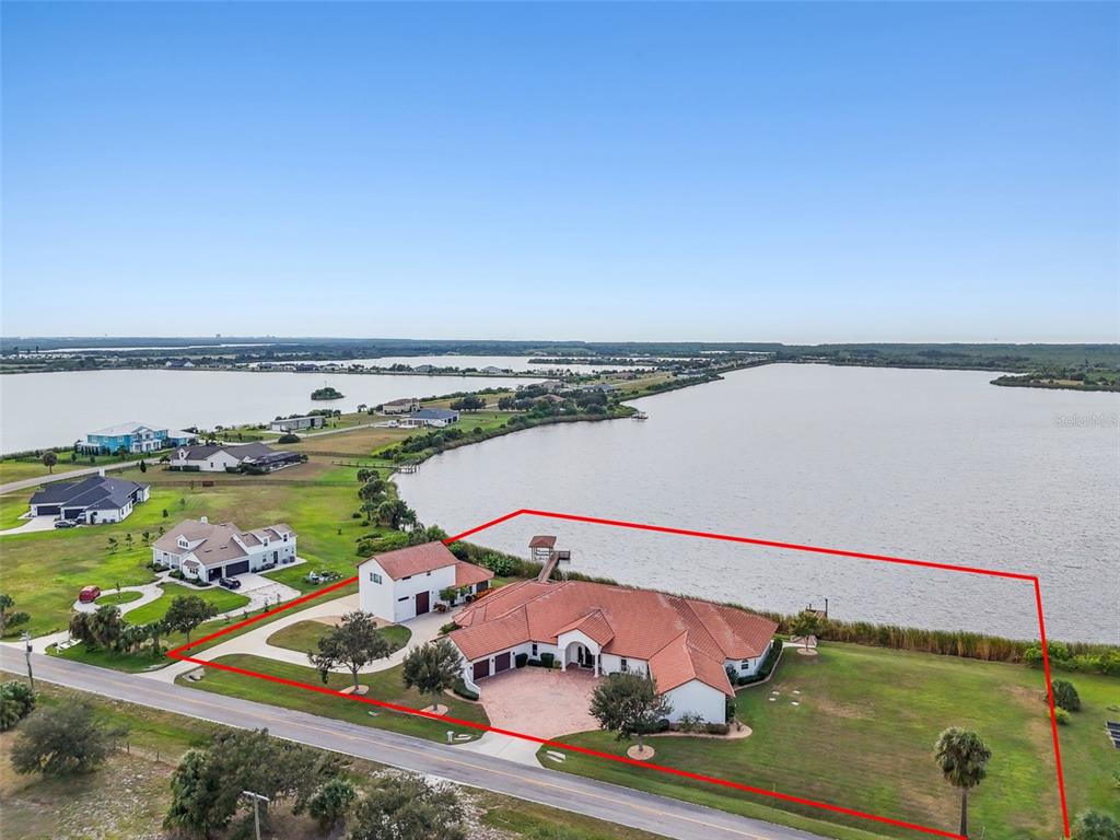 An aerial view shows a house with a red tile roof beside a large lake — 3215 GULF CITY ROAD, RUSKIN, FL