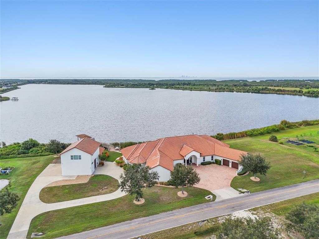 An aerial view shows a house with a red tile roof situated on a lakefront lot — 3215 GULF CITY ROAD, RUSKIN, FL