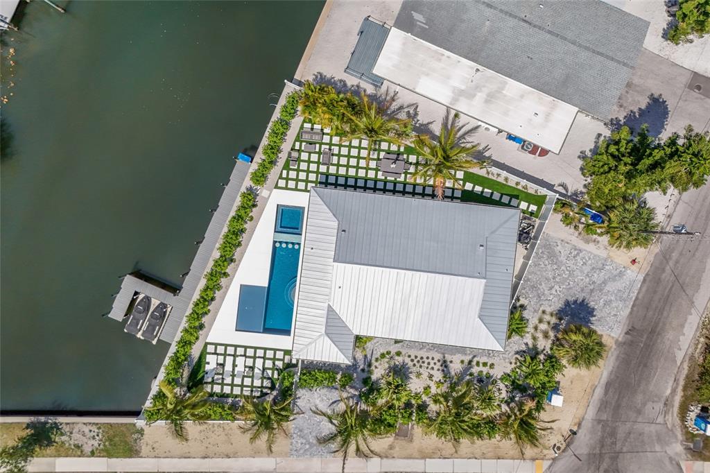 An aerial view shows a waterfront house with a pool, dock, and landscaped yard — 6401 MARINA DRIVE, HOLMES BEACH, FL