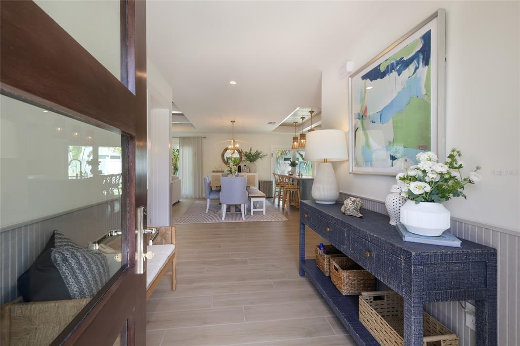 A foyer with a blue console table leads into an open-concept dining and kitchen area — 6401 MARINA DRIVE, HOLMES BEACH, FL