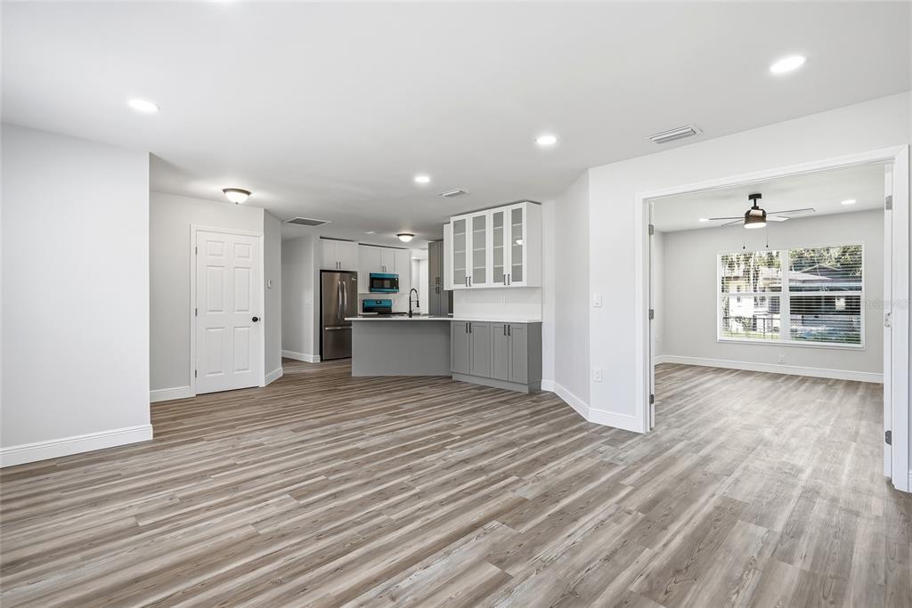 A kitchen with gray cabinets and a peninsula opens into a living area with wood-look flooring — 34641 DOGWOOD DRIVE, DADE CITY, FL