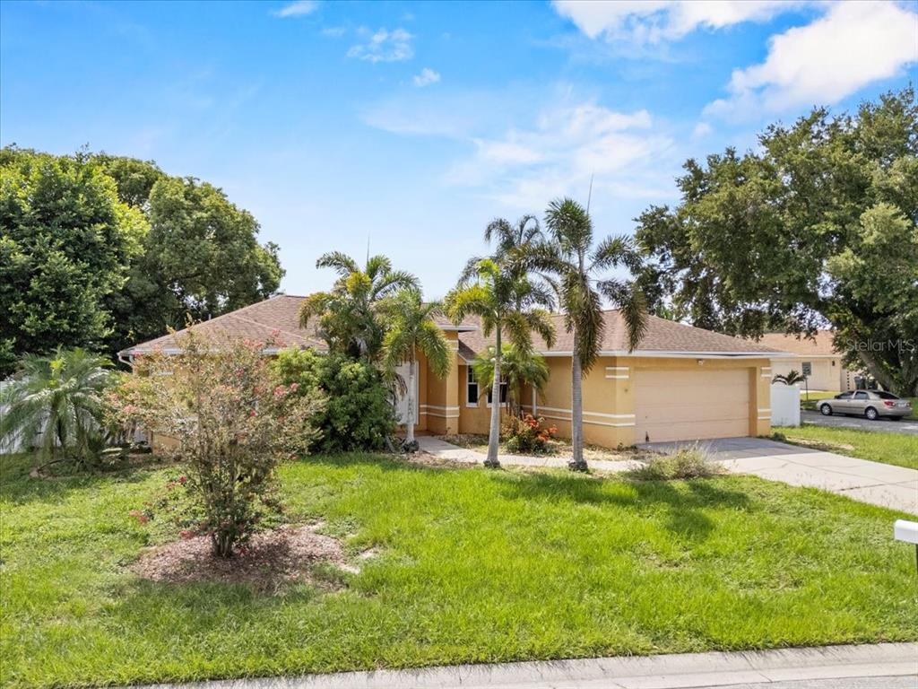 A single-story tan house with a two-car garage and palm trees in the front yard — 307 STERLING DRIVE, WINTER HAVEN, FL