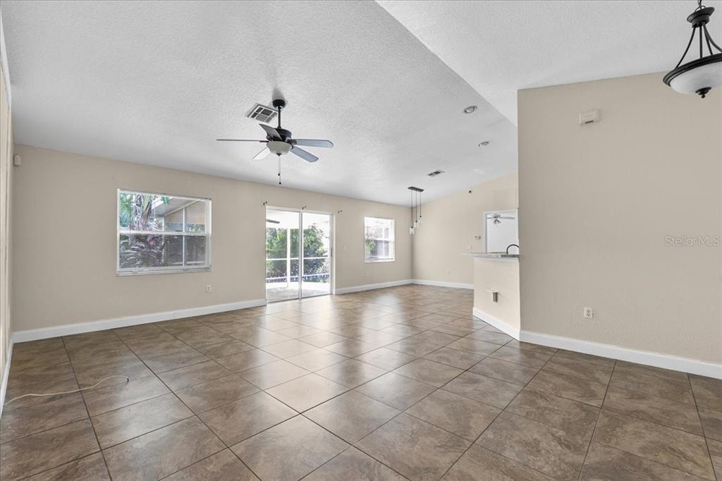 An open-concept living area features beige walls, tile flooring, a ceiling fan, and sliding doors — 307 STERLING DRIVE, WINTER HAVEN, FL