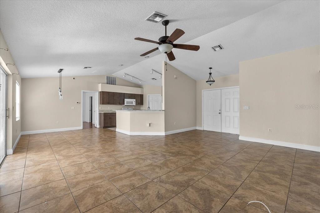 A spacious living area features tile flooring, a vaulted ceiling with a fan, and kitchen — 307 STERLING DRIVE, WINTER HAVEN, FL