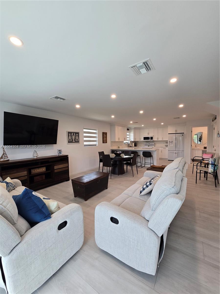 An open-concept living room and kitchen with light wood-look flooring and white cabinetry — 94825 Overseas Hwy #187, Key Largo FL 33037, KEY LARGO, FL