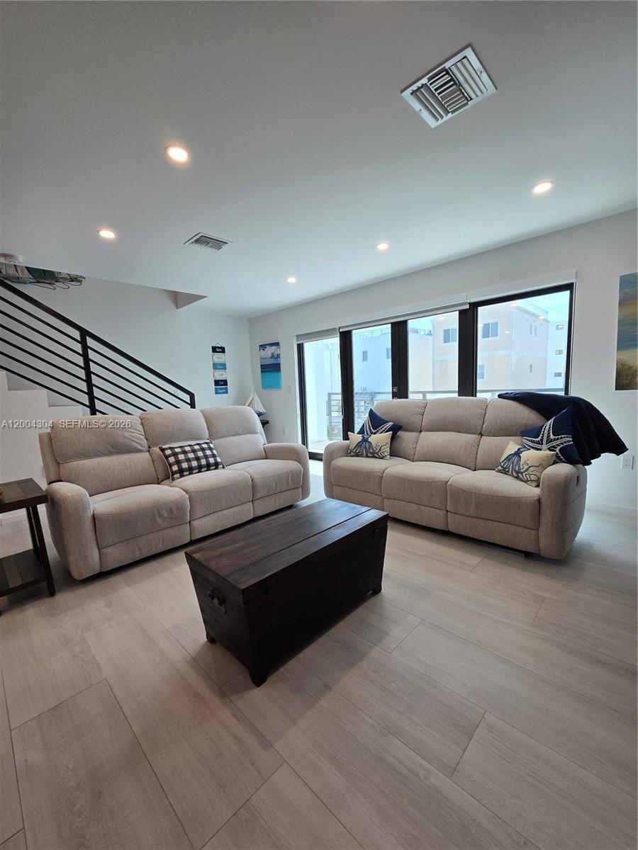 A living room features two light-colored sofas, a wooden coffee table, and a staircase — 94825 Overseas Hwy #187, Key Largo FL 33037, KEY LARGO, FL