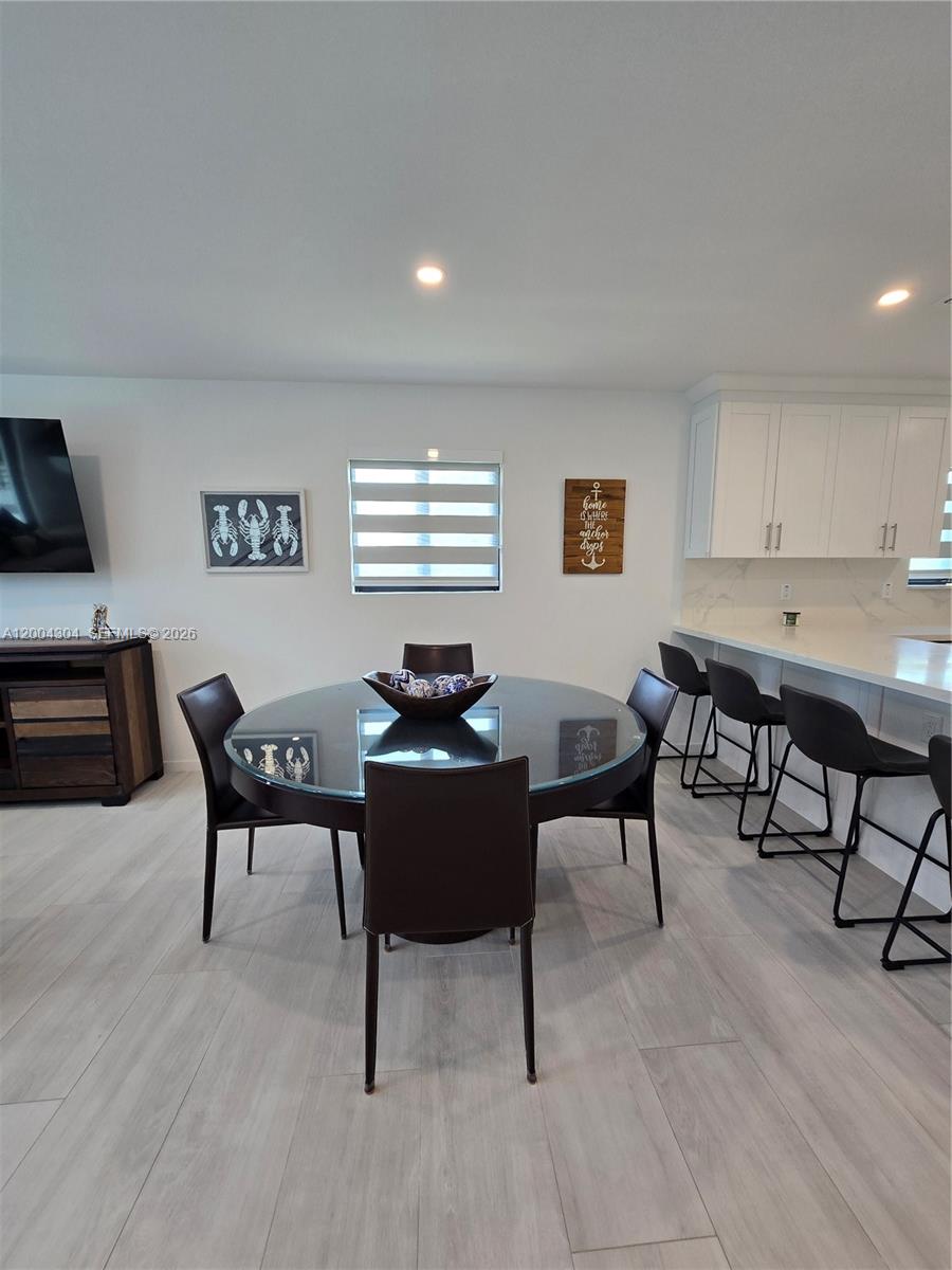 A dining area with a glass-topped table and dark chairs sits beside a kitchen island — 94825 Overseas Hwy #187, Key Largo FL 33037, KEY LARGO, FL