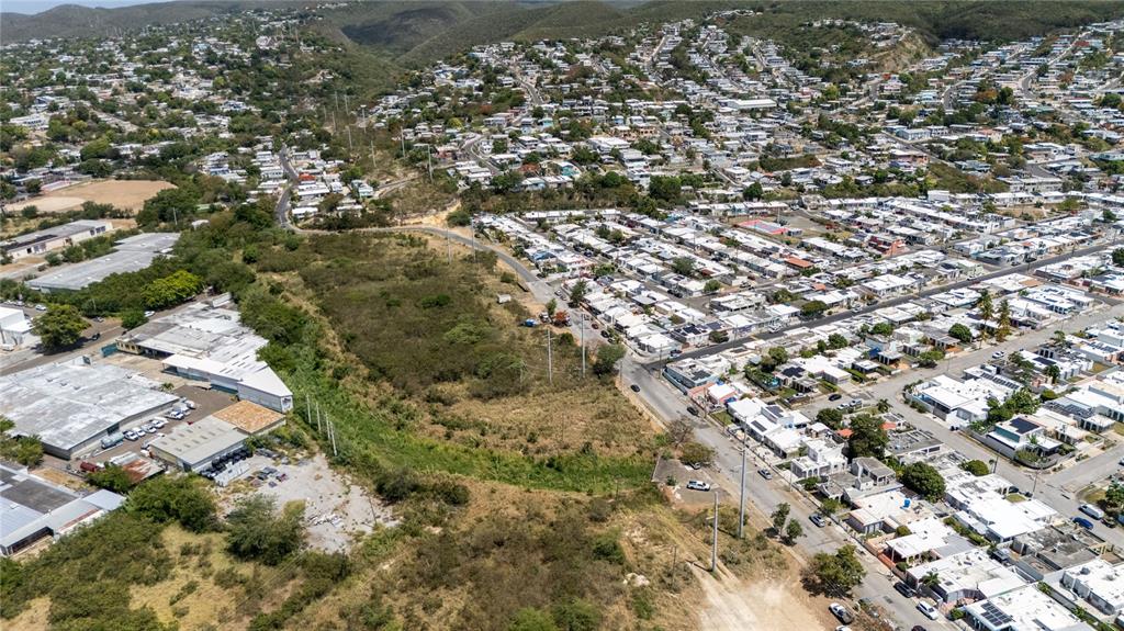 An aerial view shows a residential neighborhood bordering a large, undeveloped grassy lot — 1 REPARTO INDUSTRIAL, PONCE, PR