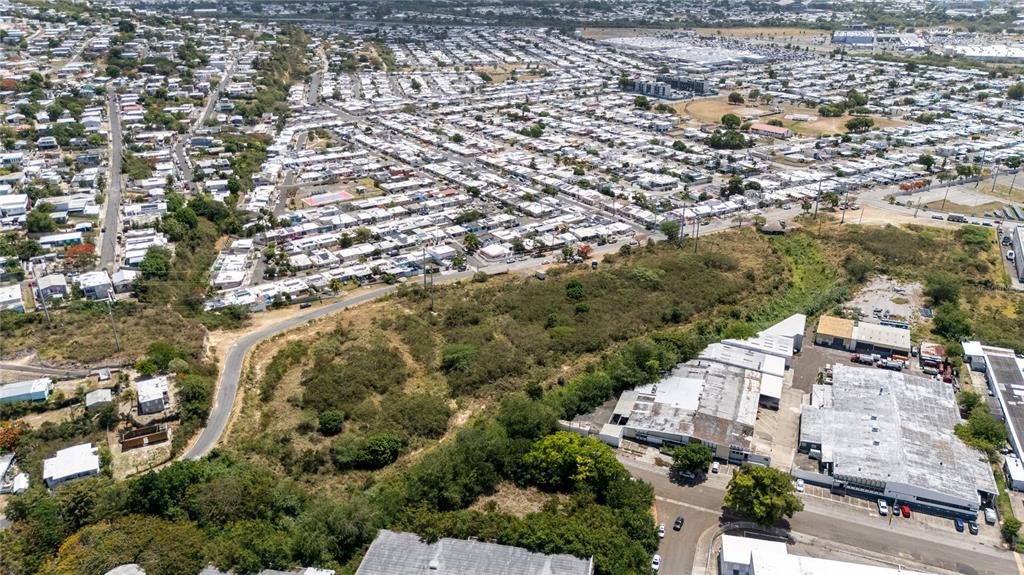 An aerial view shows a residential neighborhood adjacent to a commercial area and undeveloped land — 1 REPARTO INDUSTRIAL, PONCE, PR