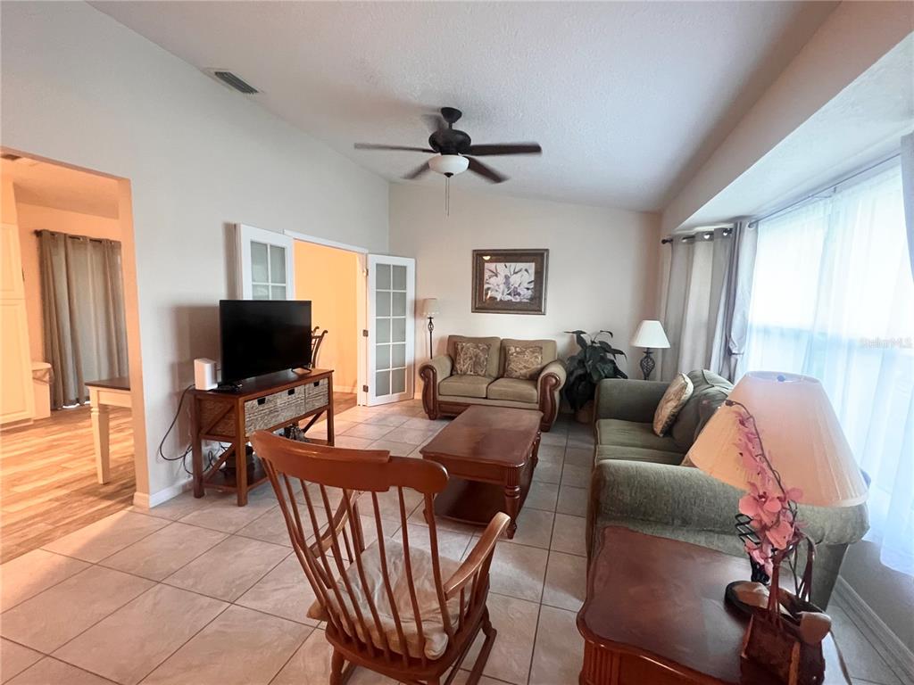 A living room features tile flooring, a ceiling fan, French doors, and traditional furniture — 20362 EMERALD AVENUE, PORT CHARLOTTE, FL