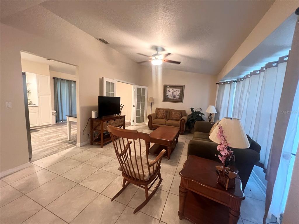 A living room features tile flooring, a ceiling fan, a rocking chair, and French doors — 20362 EMERALD AVENUE, PORT CHARLOTTE, FL