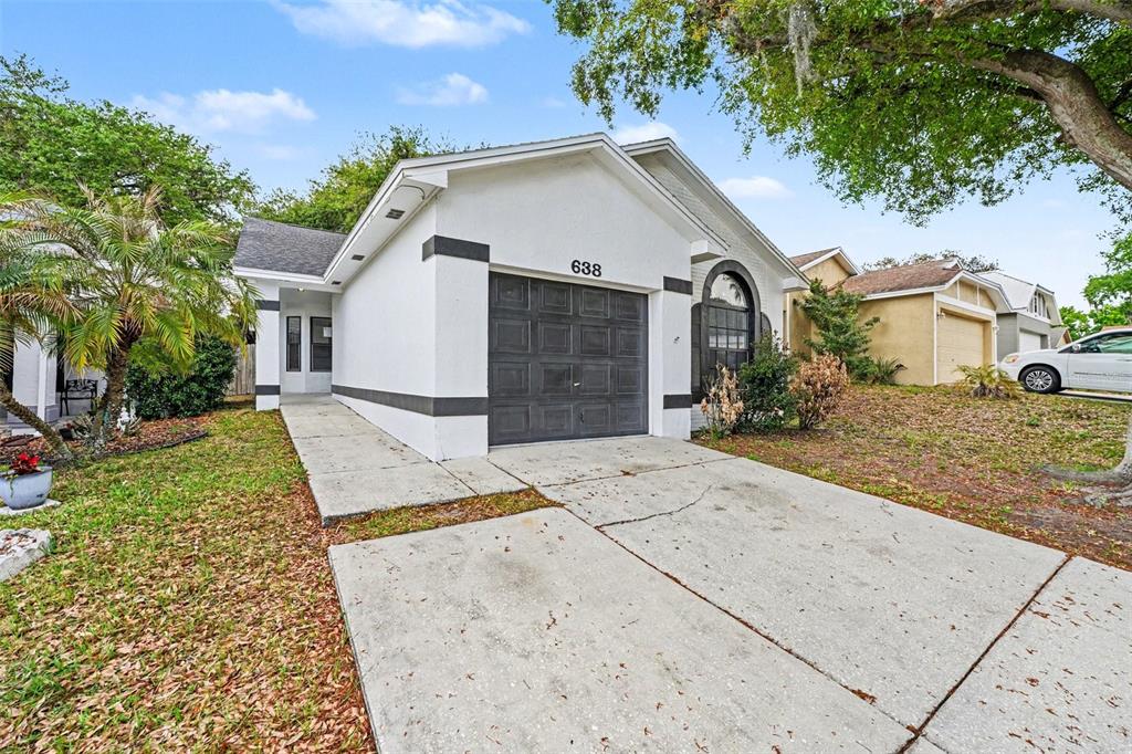 A white single-story house with a dark garage door and a concrete driveway — 638 LAKE DEXTER CIRCLE, WINTER HAVEN, FL