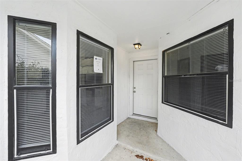 A white exterior entryway features a white door, two windows with black frames, and lighting — 638 LAKE DEXTER CIRCLE, WINTER HAVEN, FL
